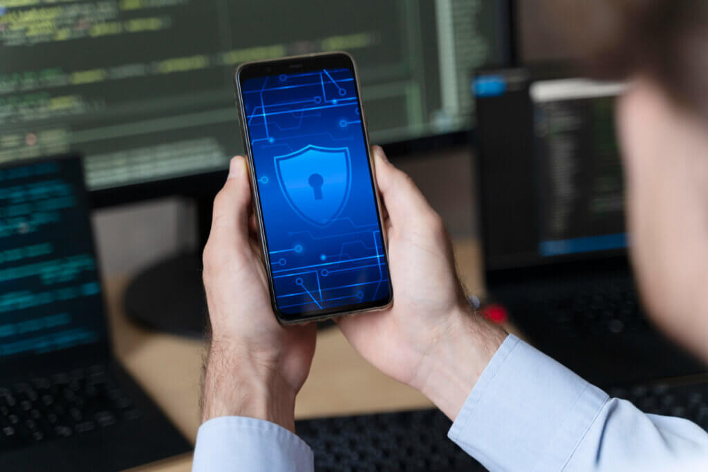 Person holding phone with cybersecurity icon displayed.